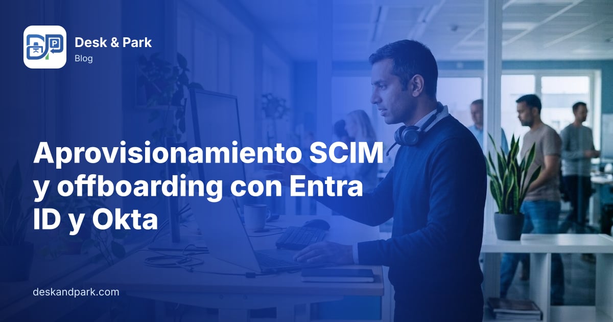 Un administrador de TI con los auriculares al cuello trabaja de pie con un portátil y un monitor